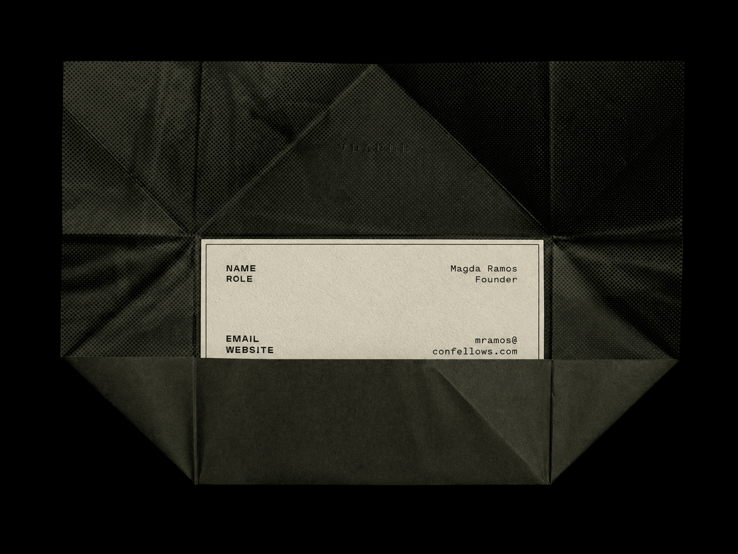 Green folded paper with a beige business card on a black background